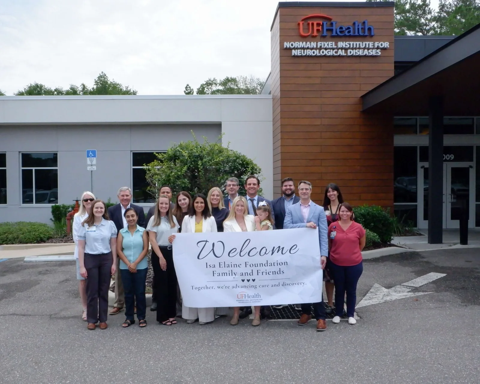 Isa Elaine Foundation family, friends, board members, and the UF Health care team outside the Norman Fixel Institute holding a welcome banner on opening day